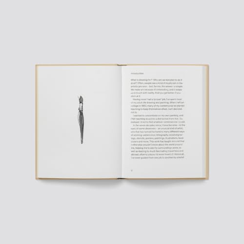 Open hardcover art book with a paintbrush illustration on white pages.