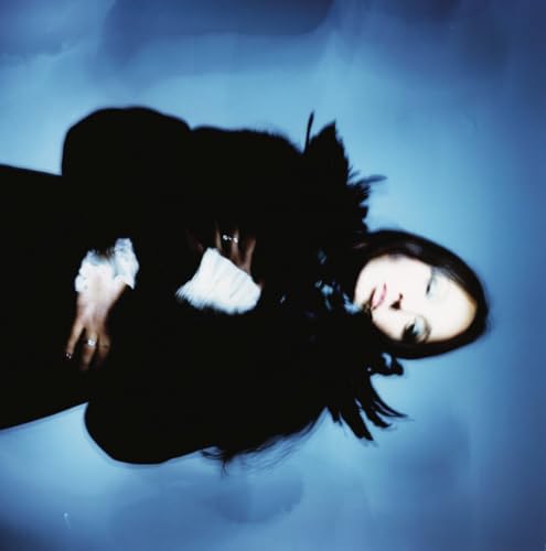 Woman with long dark hair lying down, looking at the camera.