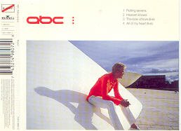 A man in a red shirt sits on a white structure outdoors.