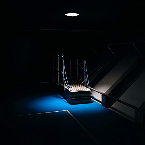 Dark stage with blue light illuminating steps and metal railings.