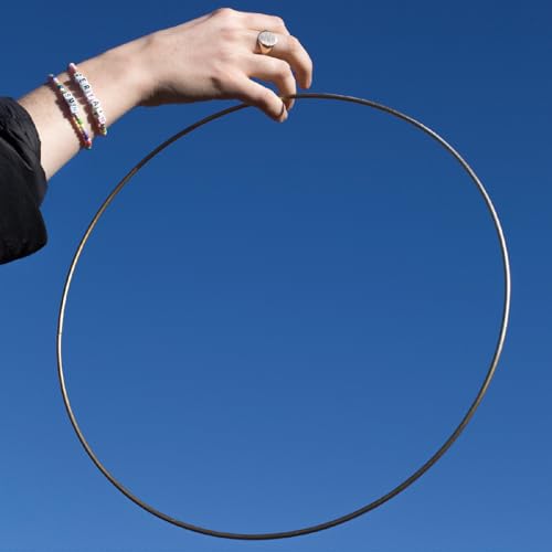 Hand holding a thin metal circle against a bright blue sky.