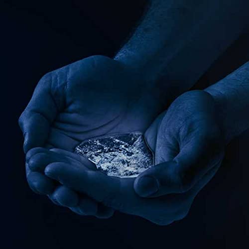 Hands cupping a textured, dark object against a black background.