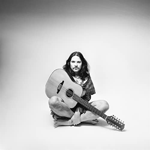Black and white portrait of a musician seated with a guitar.