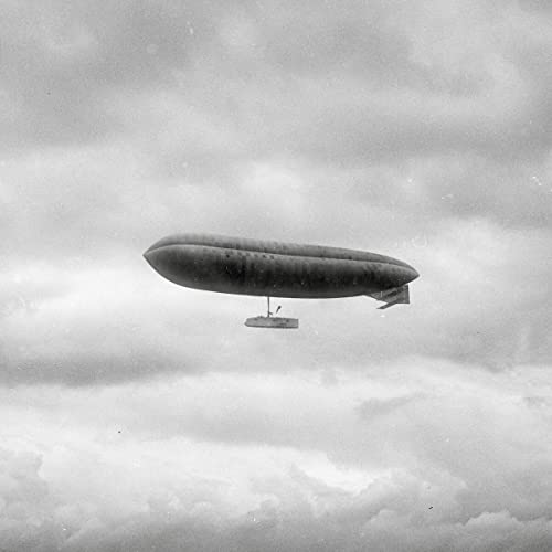 Black and white photo of a large airship in a cloudy sky.