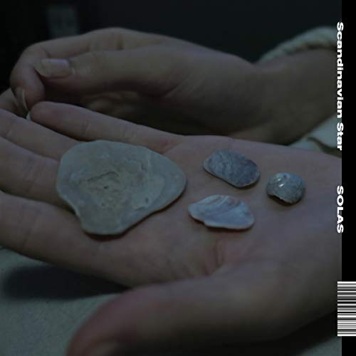 Hand holding small, grey stones against a dark, textured background.