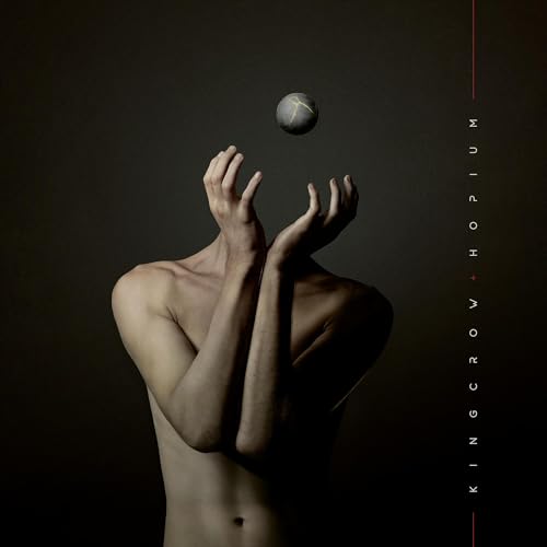 Torso with raised hands balancing a sphere against a dark background.