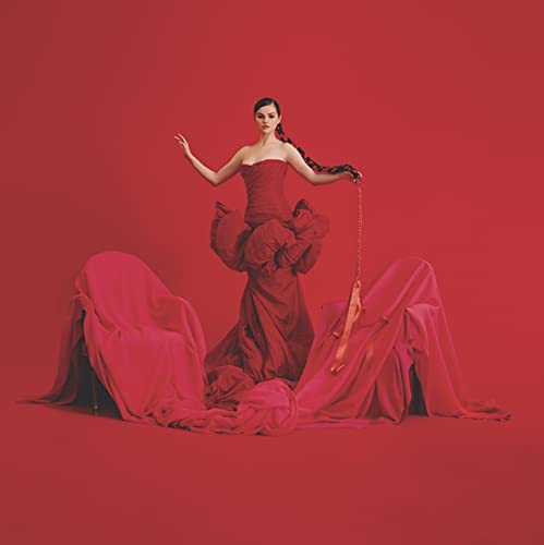 Selena Gomez in a red dress posing against a red background.