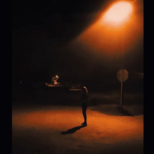 Silhouetted figure under a bright street light at night.