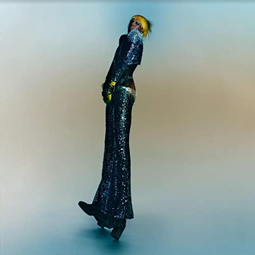 Person in glittering outfit tilted back against a pale background.