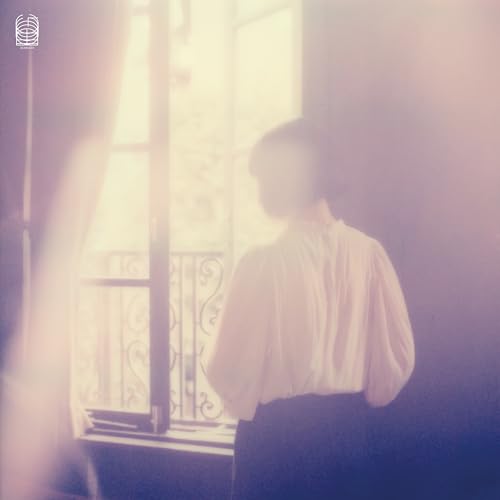 Person seen from behind, looking out a window with soft light.