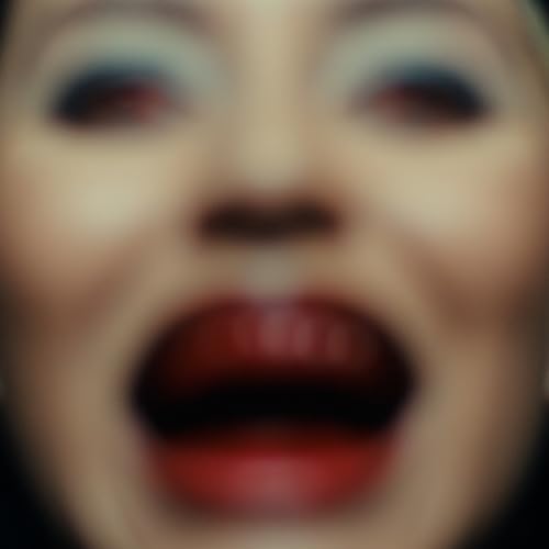 Blurred close-up of a person’s face with open mouth and red lips.