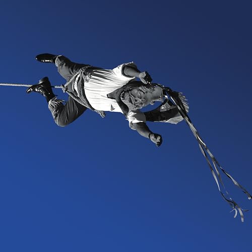Black and white image of a person balancing on a rope mid-air.