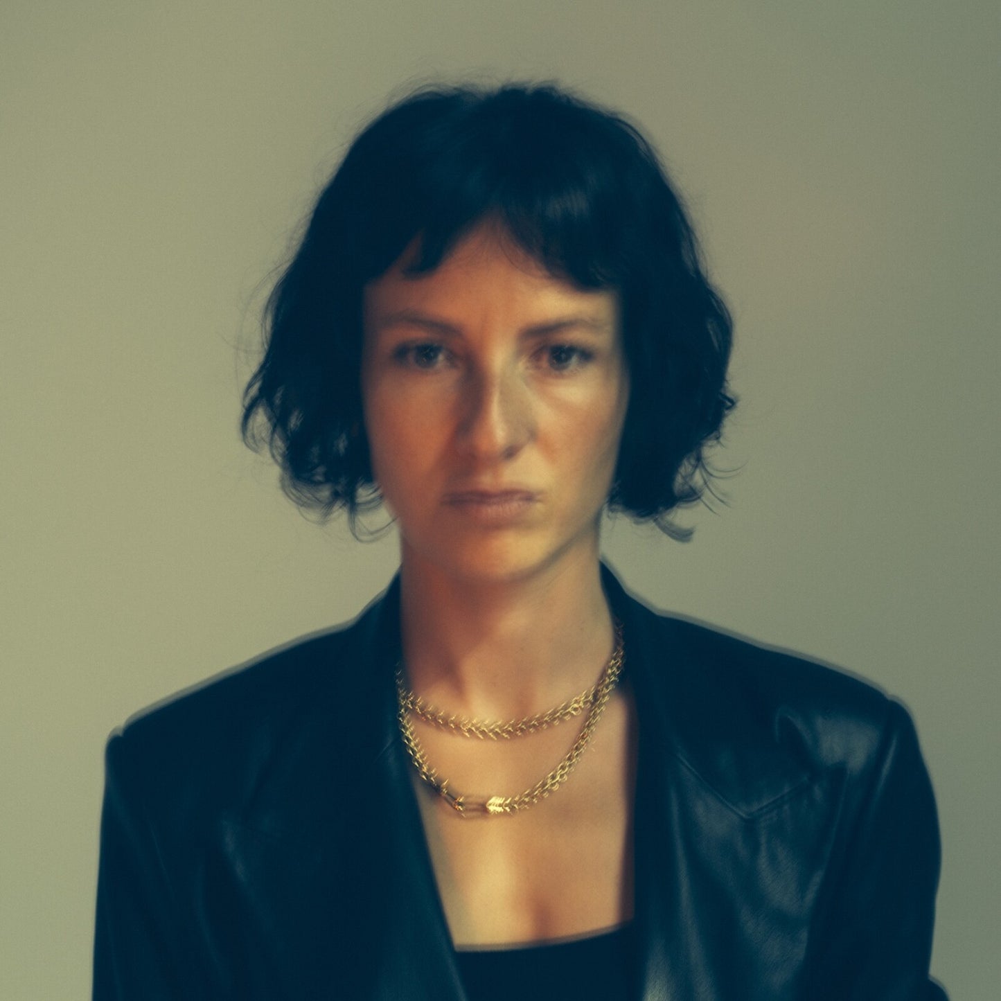 Portrait of Lea Maria Fries with short dark hair and layered gold necklaces.
