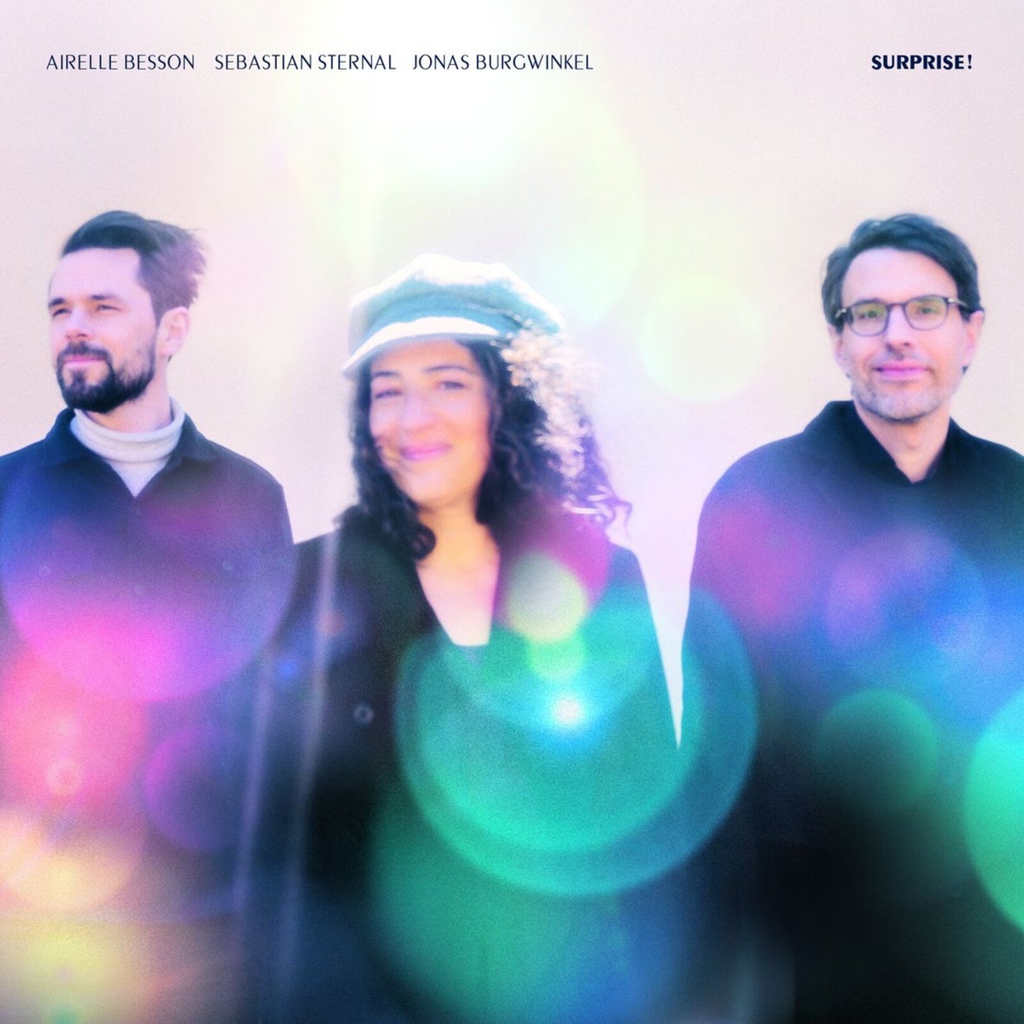 CD cover featuring three smiling people against a colorful, blurred background.