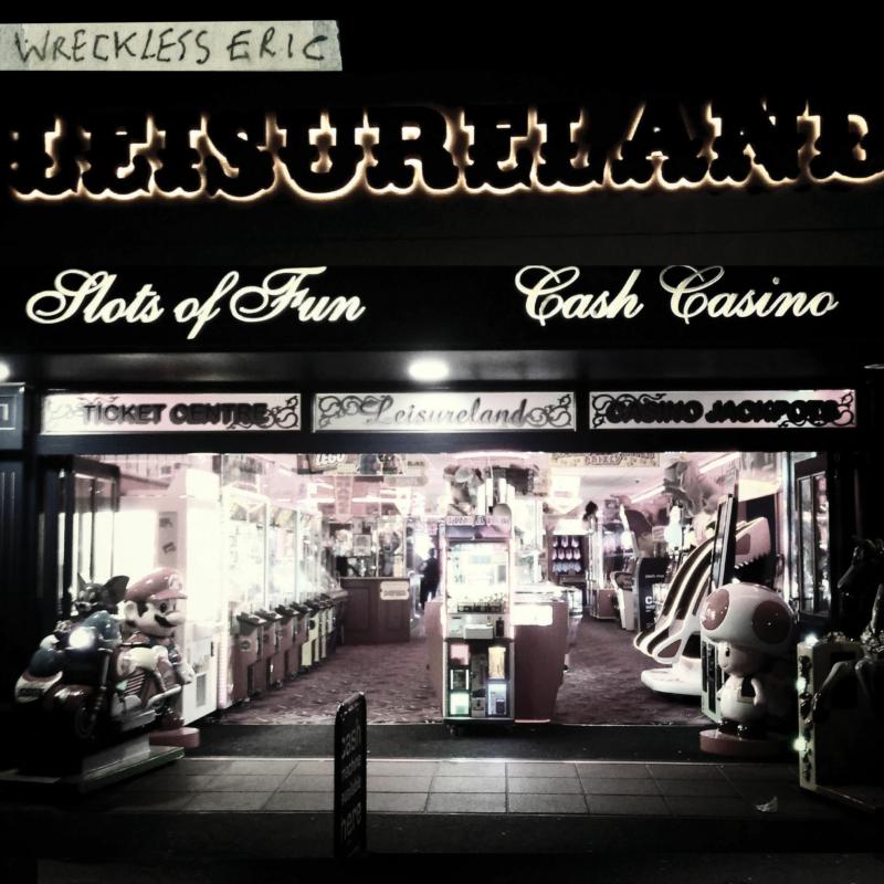 Nighttime view of a brightly lit arcade, “Leisureland” sign above.