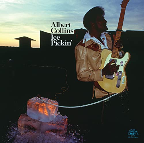 Albert Collins holding a guitar, with ice and a building backdrop.