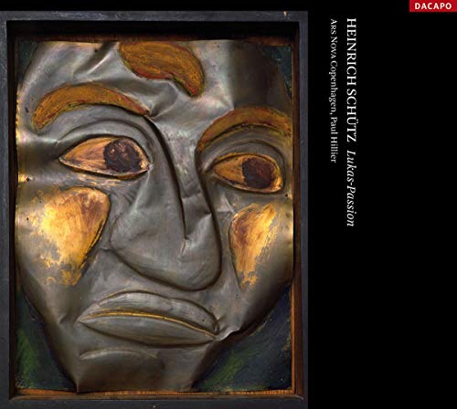 Close-up of a weathered, gilded wooden mask with painted eyes.