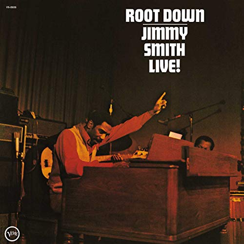 Jimmy Smith playing organ live on stage with one arm raised on album cover.