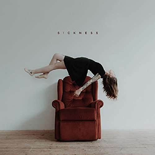 Person suspended above a red recliner on a wooden floor.
