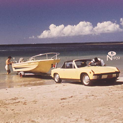 A yellow car on a beach towing a boat into the water.
