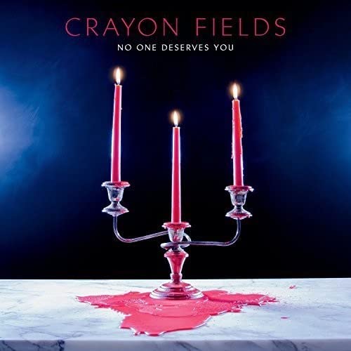 Three lit red candles in a silver candelabra on a marble surface with wax.