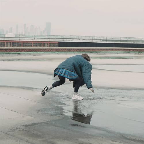 Person in a puffer jacket bending over on a wet rooftop.