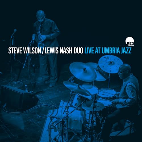 A saxophonist and a drummer performing on stage in a blue-toned concert photograph.