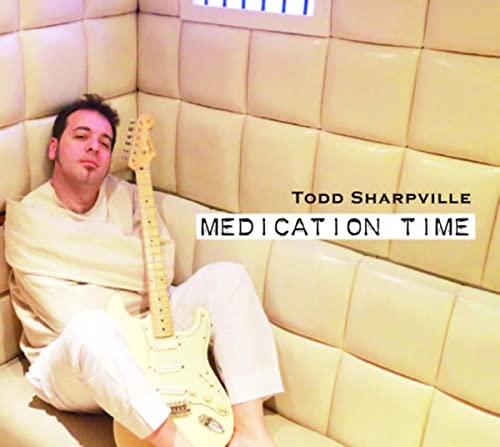 CD cover: man with guitar on a cream, cushioned wall.
