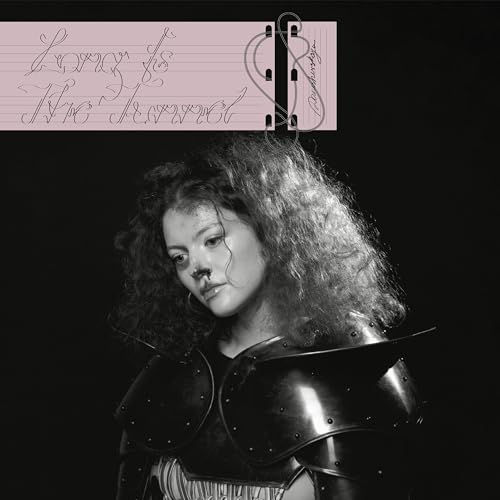 A person with curly hair wearing dark armor against a black background.