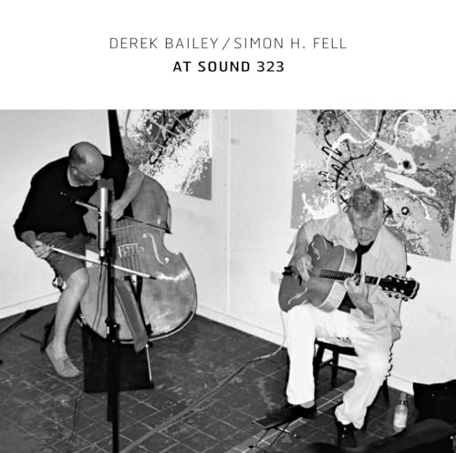 Black and white photo of two musicians playing instruments indoors.