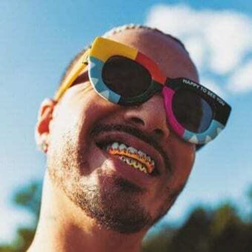 Close-up of J Balvin wearing colorful sunglasses and gold teeth.