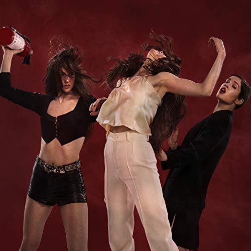 Three women with long, dark hair in dynamic poses against a red background.