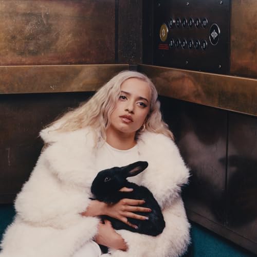 Woman with blonde hair holds a black rabbit in a faux fur coat.