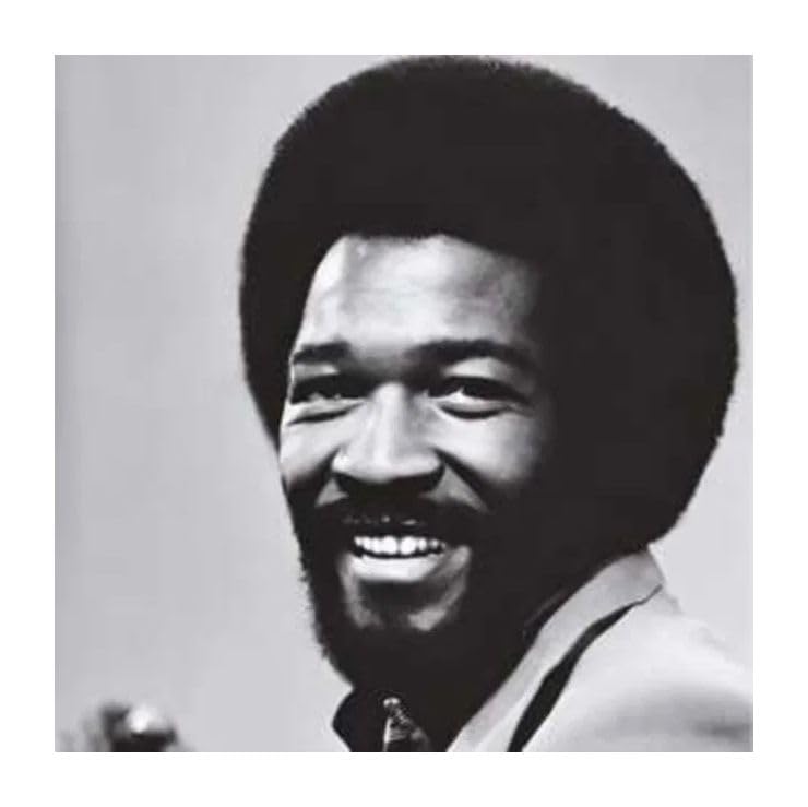 Black and white portrait of a smiling man with an afro.