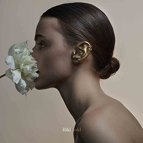 Profile of a woman with a white flower and gold ear.