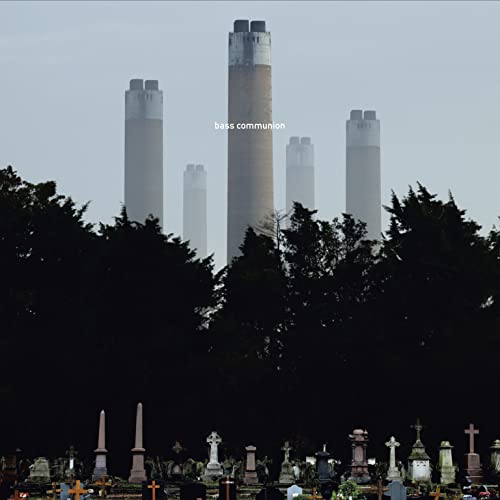 Cemetery foreground with tall industrial chimneys in a hazy background.
