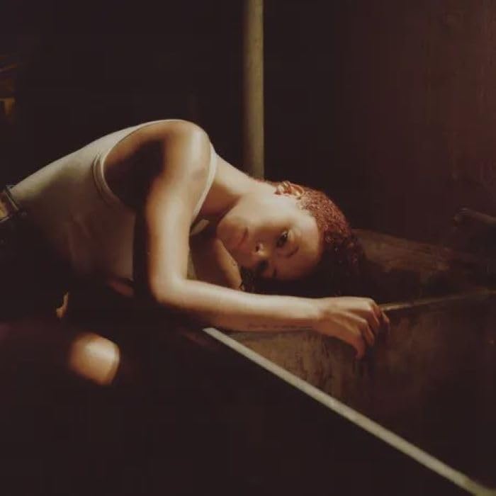 Ravyn Lenae reclines in a vintage bathtub, looking at the viewer.