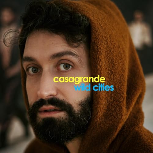Close-up of a bearded man in a brown hooded garment, album cover.