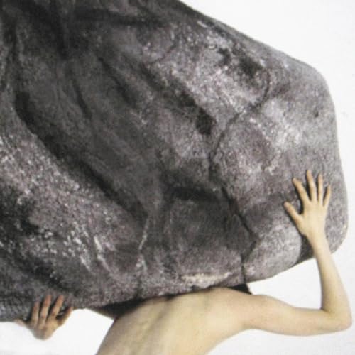 Person straining to hold up a large, textured grey rock.