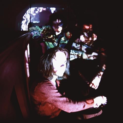 Dark, blurry image of four people with long hair, looking at a screen.