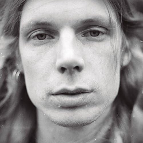 Close-up black and white portrait of a young man with long hair.