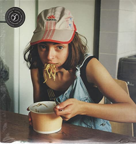 Woman with Adidas cap eating noodles, album cover for Stella Donnelly.