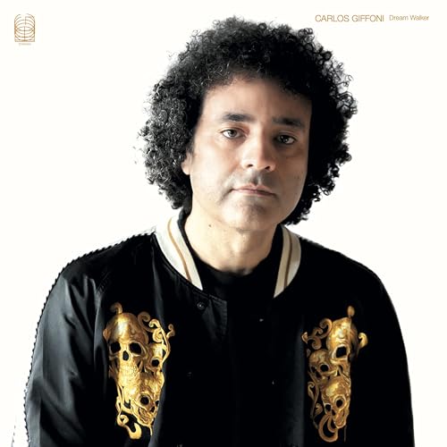 Portrait of Carlos Giffoni with curly hair and a black jacket.