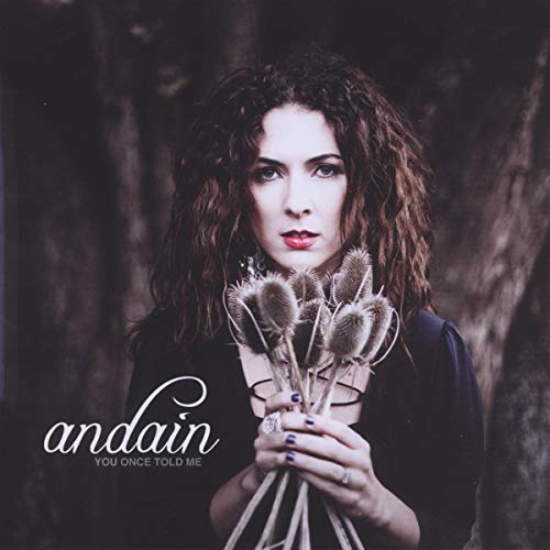 Woman with curly hair holding dried flowers, album cover art.