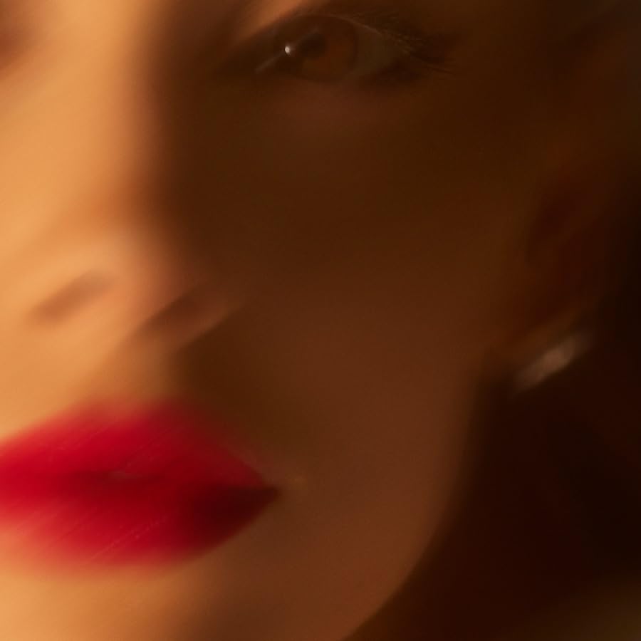 Close-up of Ariana Grande with red lips and blurred features.
