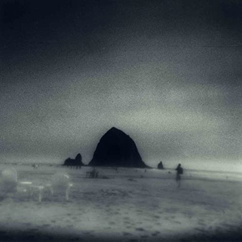 Grainy black and white photo of Haystack Rock on a misty beach.