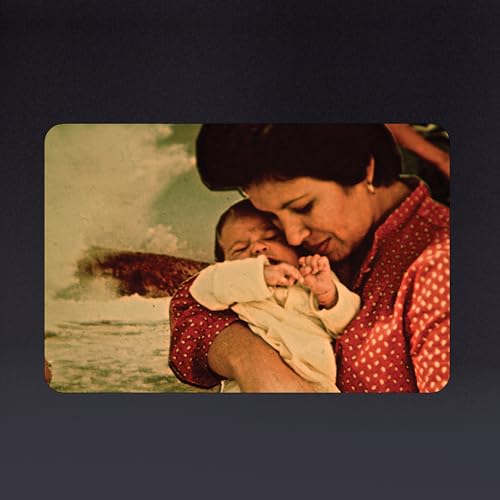 Vintage photo of a woman holding a sleeping baby, ocean background.