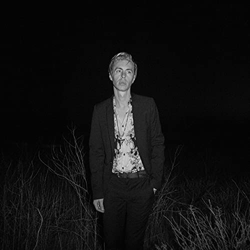 Black and white portrait of a man in a suit, outdoors at night.