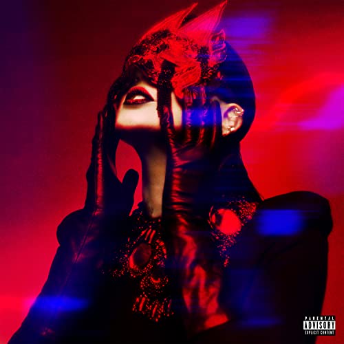 Woman with veiled face and red accents, dark clothing, dramatic lighting.