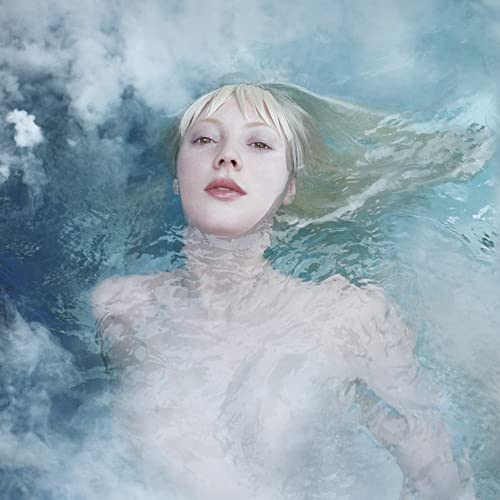 Woman with pale hair floating in blue, cloudy water.